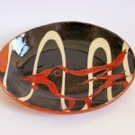 Ceramic dish with abstract yellow and red lines on white background