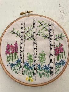 Stitched textile piece of trees and flowers on circular cloth