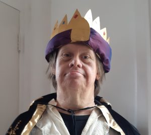 Man dressed in a king costume, with purple and gold crown