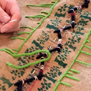 A closeup photo of a hand stitching fabric with green thread 