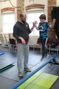 Male tutor helping young student on trapeze bar
