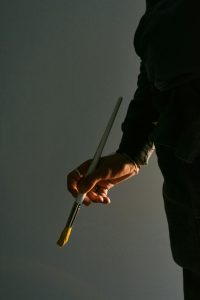 Photograph of man's hand holding paintbrush