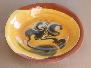 A yellow dish with a dark spiral effect on the front